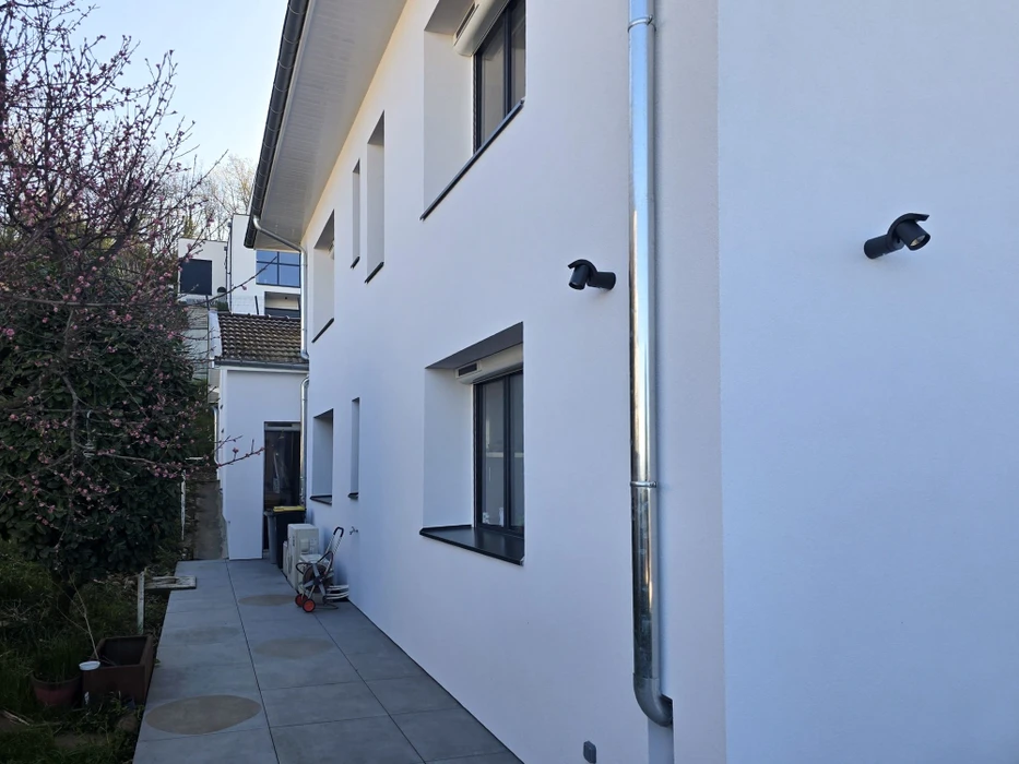 Façade latérale d'une maison contemporaine, enduit blanc, fenêtres à dormant aluminium anthracite