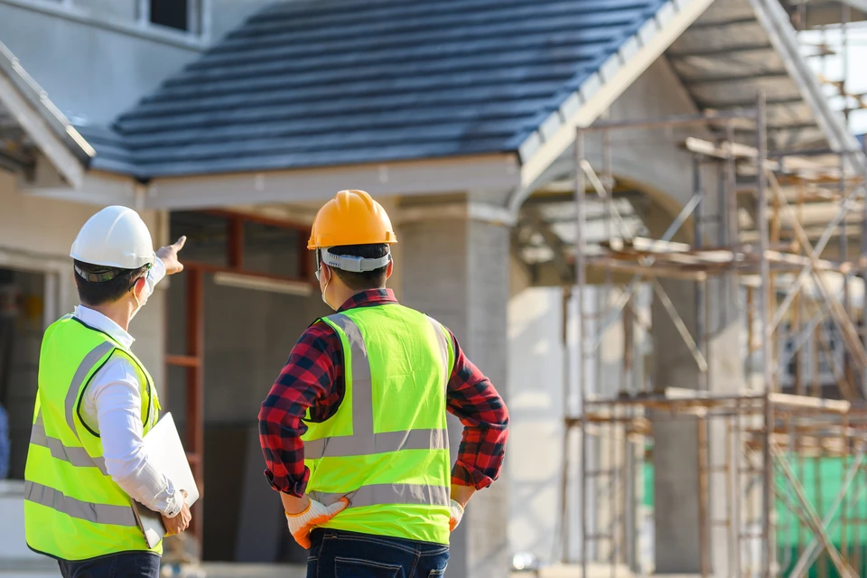 Deux professionnels du bâtiment observent un chantier de construction résidentielle