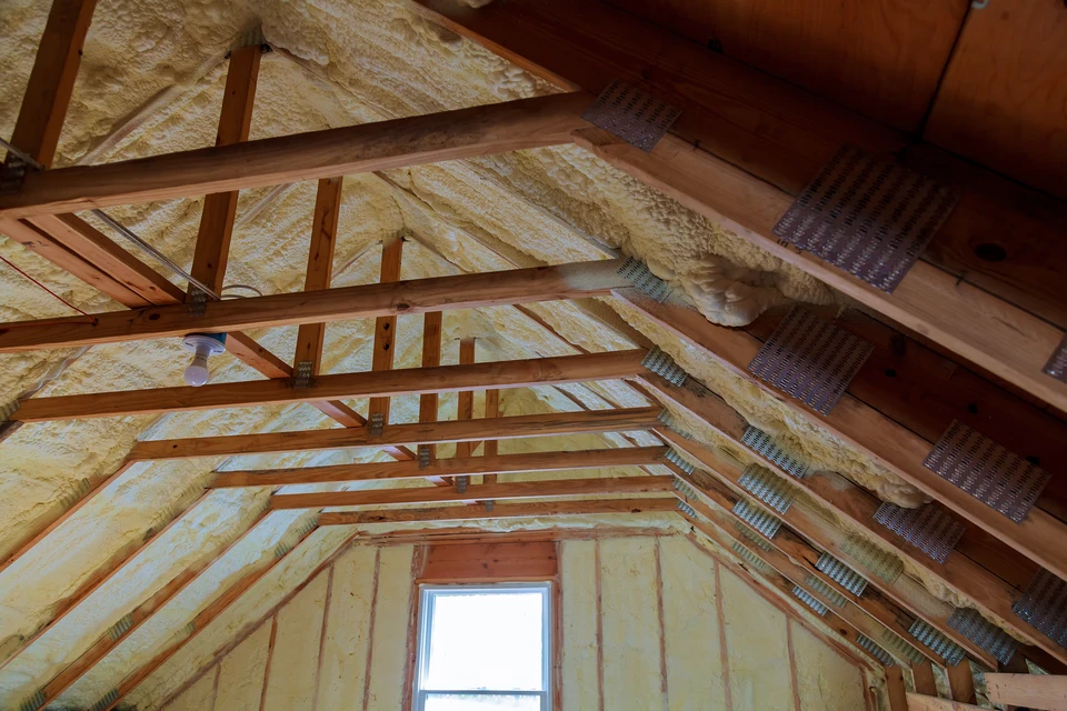 Chantier de construction résidentielle en cours, combles aménageables avec charpente bois apparente et isolation thermique jaune entre chevrons