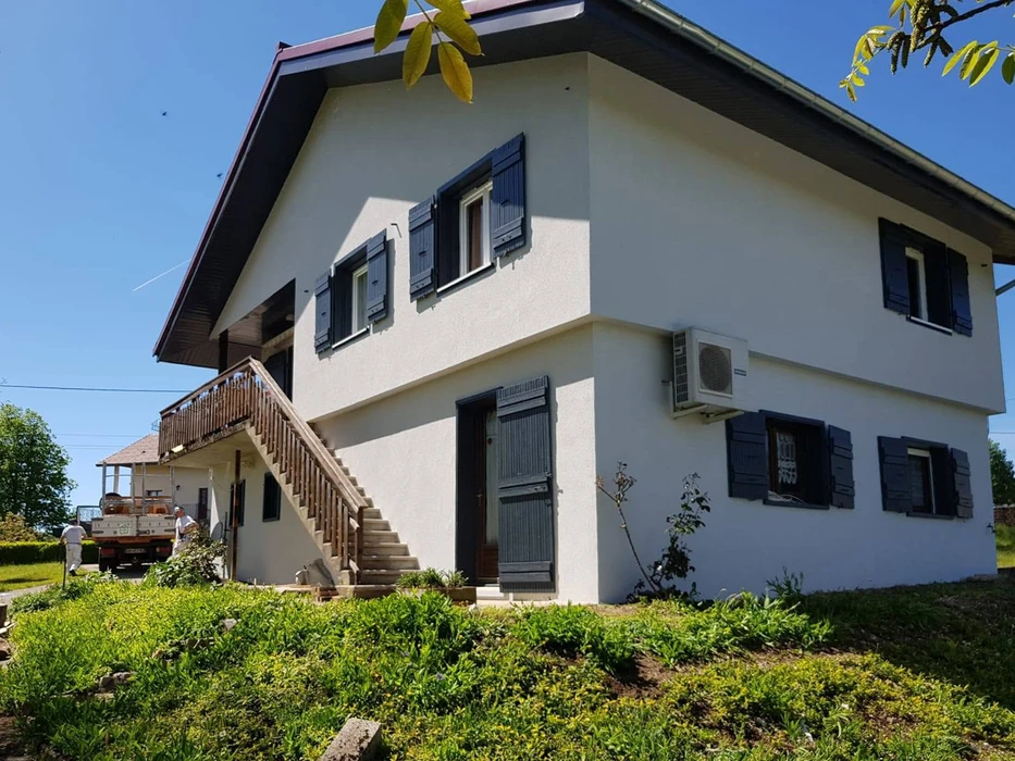 Façade extérieure d'une maison individuelle à deux niveaux, enduit blanc, avec terrasse