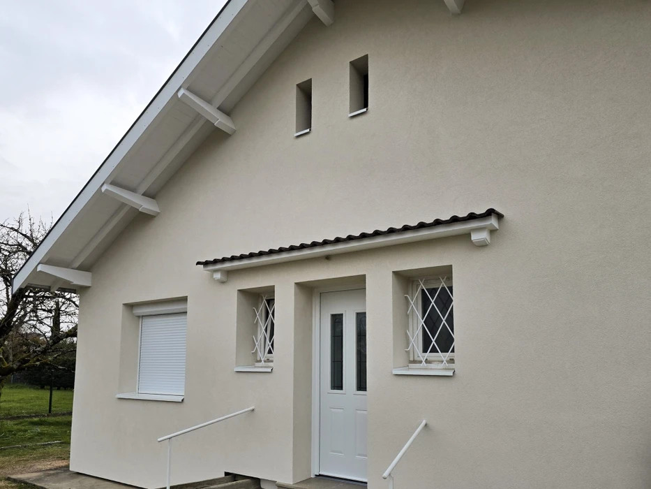 Façade latérale d'une maison individuelle contemporaine, enduit monocouche teinte sable clair