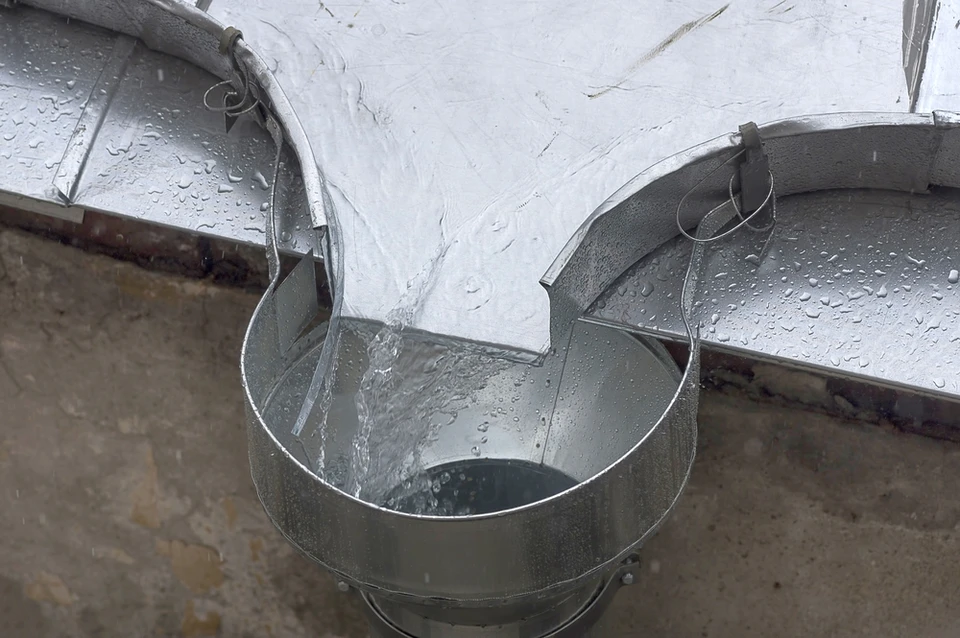 Extérieur sous forte pluie, gouttière métallique ondulée installée sur structure bois