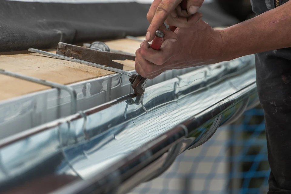 Gros plan sur une gouttière en aluminium avec système de protection anti-feuilles installé sur le rebord d'un toit résidentiel