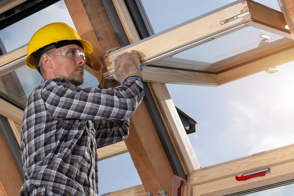Combles en cours d'isolation thermique avec ossature bois apparente et fenêtre de toit installée