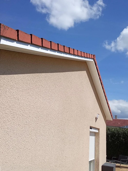 Ouvrier en vêtements de protection blancs travaillant sur échafaudage métallique devant façade de bâtiment en rénovation