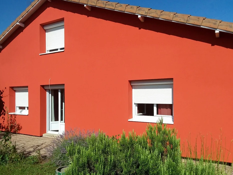 Maison individuelle plain-pied, façade enduit crépi beige, toiture tuiles terracotta avec charpente apparente bois brun