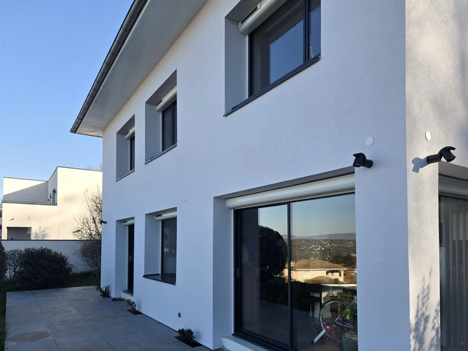 Maison individuelle plain-pied, façade enduit crépi beige, toiture tuiles terracotta avec charpente apparente bois brun