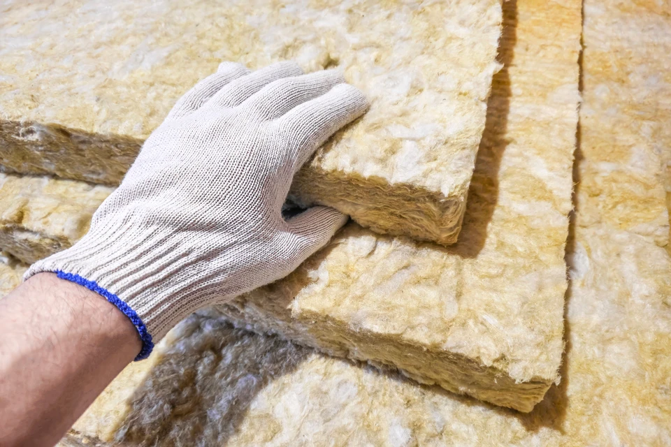 Chantier de construction résidentielle, ouvriers installent isolation thermique entre solives de plancher